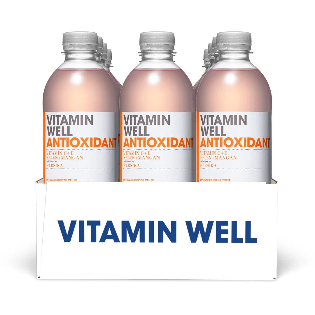 12 x Vitamin Well 500 ml Antioxidant Persika i ett vitt flak med genomskinliga plastflaskor och ljusrosa dryck.
