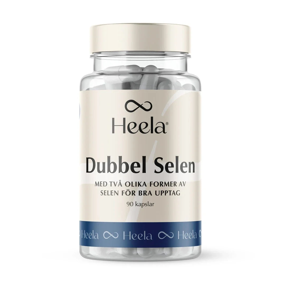 Heela Dubbel Selen 100 µg 90 caps i en transparent plastburk med ljusbeige etikett, blå bas och synliga vita kapslar.