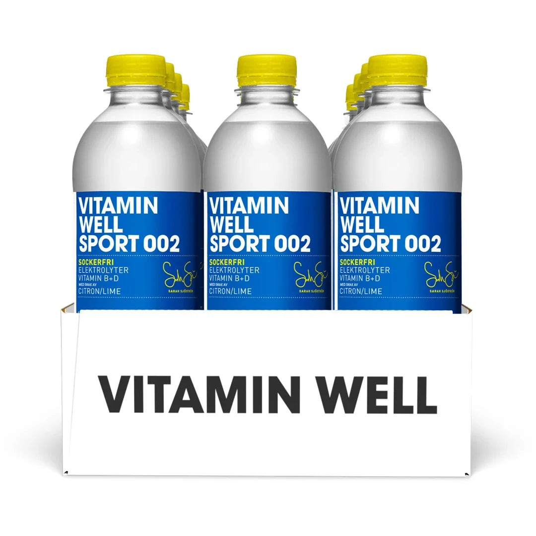 12 x Vitamin Well Sport 500 ml 002 - Lemon Lime (sockerfri) i ett vitt flak med flaskor, blå etiketter och gula korkar.