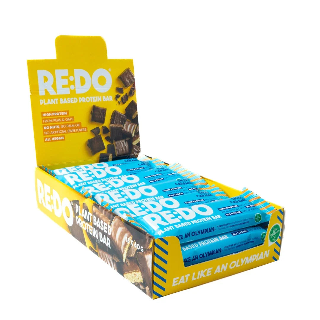 18 x REDO Bar 60 g Salty Caramel i en gul displaylåda med blåa proteinbars., bild 1 av 1