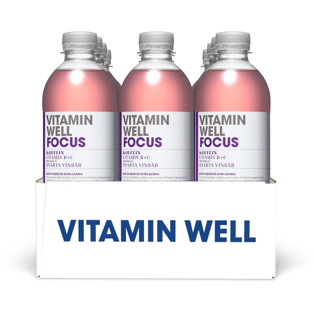 12 x Vitamin Well 500 ml Focus Svarta Vinbär i en vit kartong med klara plastflaskor, rosa dryck och lila detaljer.